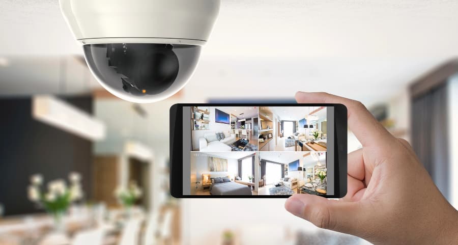 Homeowner holding smartphone with video feed from security cameras in Pensacola